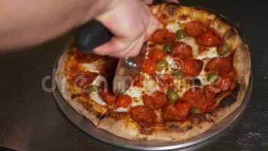 一个人用一个比萨饼切割器将一个意大利香肠比萨饼切成多片的慢动作特写
